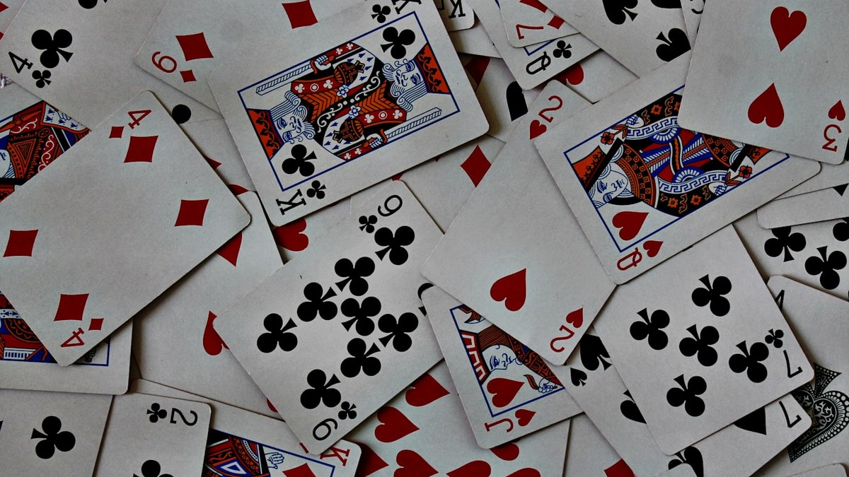 Playing cards scattered from a deck, including a queen of hearts and king of clubs.